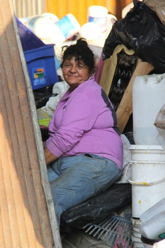 a woman sitting on the ground next to a pile of garbage